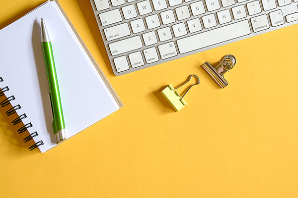Gelber Schreibtisch, Draufsicht mit Tastatur, Kabel, Stift, Notizblock