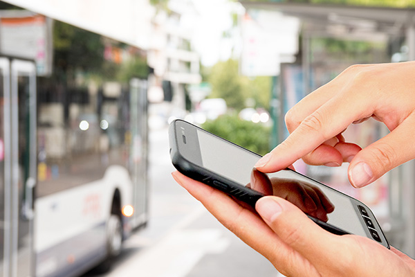 Bus stoppt an Haltestelle. Mobiltelefon, mit dem Finger auf dem Display ein Ticket für den Bus zu kaufen.